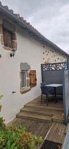 a deck with a table and a bench on a house at Chambre les orchidées in Montournais