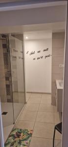 a bathroom with a shower and writing on the wall at Chambre les orchidées in Montournais
