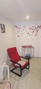 a red chair in a room with a wall with butterflies at Chambre les orchidées in Montournais