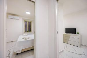 ein weißes Zimmer mit einem Bett und einem Fernseher in der Unterkunft Kiros - appartement 6 personnes - check in h24 - wifi in Lyon