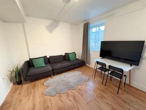 a living room with a couch and a flat screen tv at Essex Apartment in Loughton
