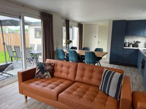 a living room with a brown couch and a table at Chalet Pareloester - Ouddorp in Ouddorp