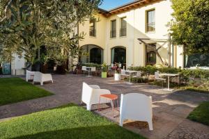 a courtyard with white chairs and tables in front of a building at The Ziba Hotel & Spa in Peschiera del Garda