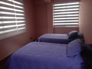 two beds in a bedroom with blue sheets and windows at Luxury House in Cochabamba +12 photos
