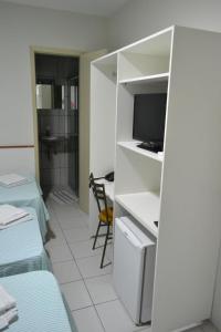 a room with a bed and a desk with a television at Hotel Itapoã in Teresina