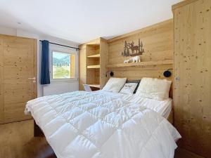 a bedroom with a white bed with a wooden wall at Le Chaberton - Les Tanières de Montgenèvre - Appartement 6 à 8 personnes front de neige in Montgenèvre