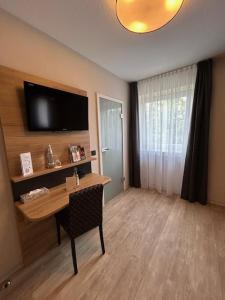 a room with a desk and a television on a wall at ParkHotel Fulda in Fulda