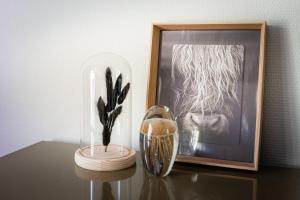 a vase on a table next to a picture and a vase at Vacation home Magnolia Veluwe in Nunspeet