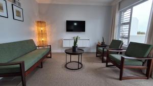 Una sala de estar con un sofá y sillas y un televisor. en Benguella Breeze, en Swakopmund