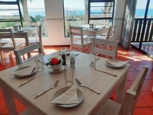 a wooden table with plates and utensils on it at OCEAN VIEW GUEST HOUSE in Jeffreys Bay