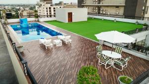 a balcony with a pool and chairs and an umbrella at Nine Tree Luxury Hotel & Suites Lahore in Lahore