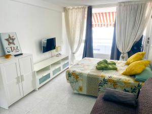 ein Schlafzimmer mit einem Bett, einem Fernseher und einer Couch in der Unterkunft Borinquen Sky Apartments in Playa de las Americas