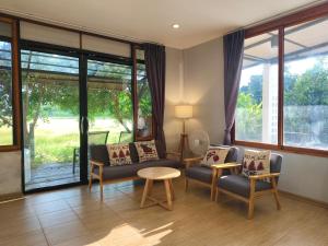 a living room with chairs and a table and windows at Minimal house in Doi Saket