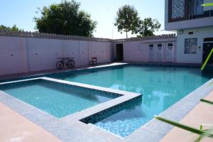 Una piscina con agua azul frente a un edificio. en Ranthambore Sawai Palace, en Sawāi Mādhopur