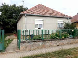a house with a green fence in front of it at Frangipáni Vendégház in Várdomb