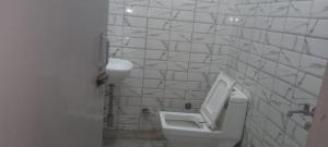 a white bathroom with a urinal and a sink at Hotel Saffron in Meerut