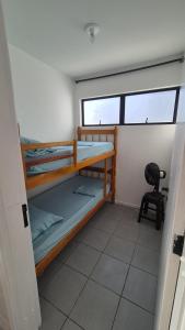 a room with two bunk beds and a chair at Ap Matinhos - Pé na areia e Vista para o Mar - Praia Brava - Caiobá in Matinhos +61 photos