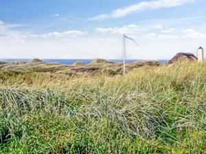 ein Feld mit hohem Gras und einer Windkraftanlage in der Unterkunft Holiday Home Hoat - 300m from the sea by Interhome in Saltum