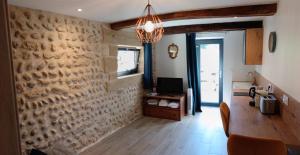 a living room with a stone wall and a chandelier at La Source Bleue in Le Chalon