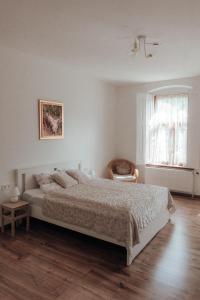 a white bedroom with a bed and a chair at Barátúri Barátok Vendégház in Barátúr
