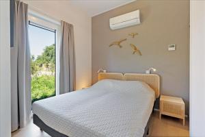 a bedroom with a bed and a window with birds on the wall at Chalet Duynhof 8 - Ouddorp in Oudeland