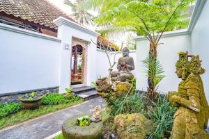a garden in front of a house with a statue at Imagine Bali in Ubud
