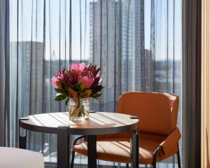 a vase of flowers on a table in front of a window at Caption By Hyatt Central Sydney in Sydney