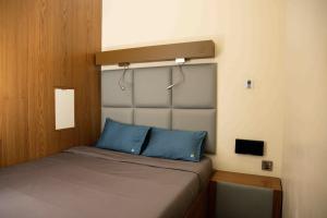 Un pequeño dormitorio con una cama con almohadas azules. en Sleepover Terminal 3, Concourse C - formerly sleep 'n fly, en Dubái