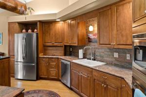 a kitchen with wooden cabinets and a stainless steel refrigerator at Spacious Sedona Splendor with Community Spa & Pool in Sedona
