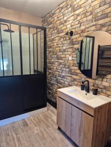 a bathroom with a sink and a brick wall at Le Millésime in Eu