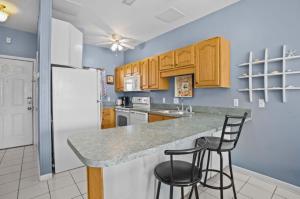 una cucina con frigorifero bianco e 2 sgabelli da bar di Baywatch F-3 a Villa Sabine