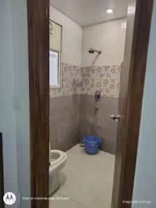 a bathroom with a toilet and a blue bucket at Hotel Banke Bihari Stays in Vrindāvan