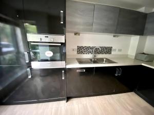 a kitchen with black cabinets and a sink at 4 Bedroom House in Milton Keynes in Milton Keynes
