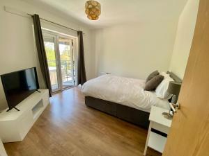 a bedroom with a bed and a flat screen tv at 4 Bedroom House in Milton Keynes in Milton Keynes