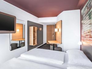 a hotel room with two beds and a flat screen tv at B&B Hotel Hamburg-Airport in Hamburg