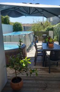a patio with a table and chairs and an umbrella at Maison de ville, Piscine, Jacuzzi et jardin privé in Bayonne