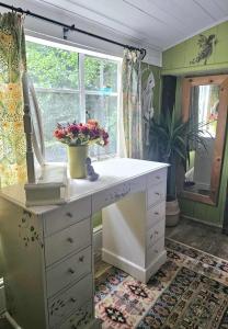 a white dresser with flowers in a room with a window at Bluebell Cottage At Lurley Manor in Washfield