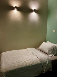 a bed with two lights on a green wall at Village 40 Phuket Old Town in Phuket