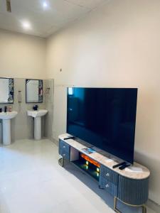 Un televisor de pantalla plana grande en una habitación con dos lavabos. en Ivory Room Lableva Court, en Lusaka