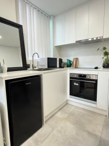 a kitchen with white cabinets and a black dishwasher at Fully equipped brand new built studio in Chipping Norton