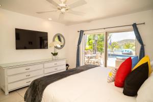 a bedroom with a bed with a television and a sliding glass door at Antigua Bay Villa in Bats Cave +24 photos