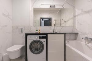 a white bathroom with a washing machine and a sink at Glow Apartments, Apartamenty Zaspa, Dywizjonu 303 in Gdańsk +28 photos