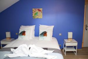 um quarto azul com uma cama com dois pássaros nas almofadas em La petite auberge de niaux em Niaux