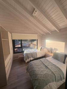 a bedroom with two beds and a window at Hoyo 5 Aldea de golf in San Martín de los Andes