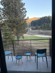 a balcony with chairs and tables and a view of a field at Hoyo 5 Aldea de golf in San Martín de los Andes