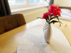 a white vase with pink flowers sitting on a table at Serviced Business Apartments Osnabrücker Land in Badbergen