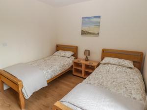 una camera da letto con due letti e un tavolo con una lampada di Awel y Môr a Burry Port