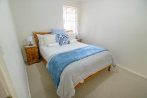 a bedroom with a bed with blue and white pillows at Coastal Garden Villa in Albany