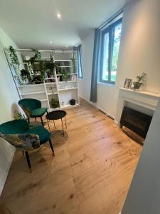 a living room with a fireplace and green chairs at Chambres de hôte les moulin la paille in Veyre-Monton