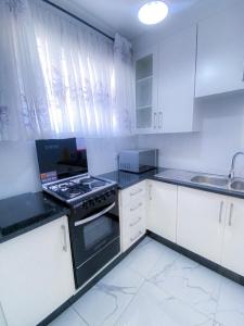 a kitchen with white cabinets and a stove top oven at Cozy Up on 5th in Harare